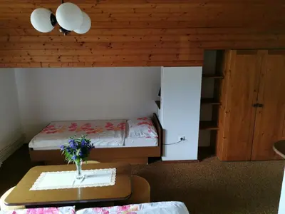 a small room with a bed and a table with flowers on it at Apartment Žvab in Bohinj