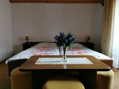 a table with a vase of flowers on it with a bed at Apartment Žvab in Bohinj