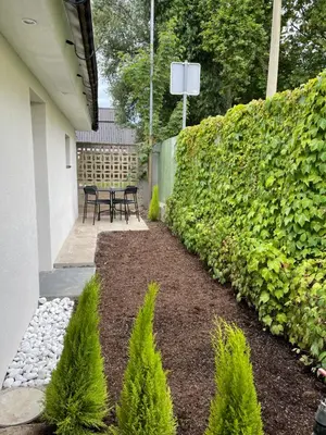 a garden with a table and chairs and a hedge at Apartma Tany in Ljubljana