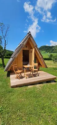 a wooden cabin with a table and a thatch roof at Glamping - Kamp Steska in Žalec