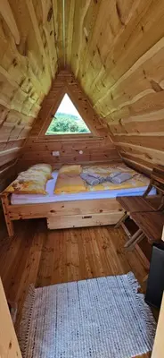 a bed in a wooden room with a window at Glamping - Kamp Steska in Žalec