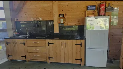 a kitchen with a white refrigerator and wooden cabinets at Glamping - Kamp Steska in Žalec