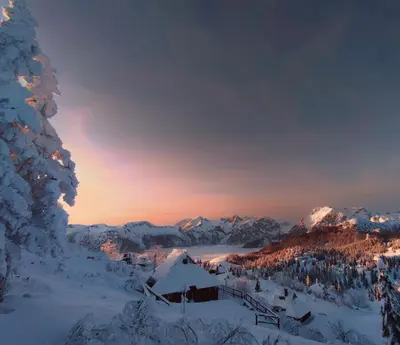 a winter scene with snow covered mountains and a lodge at Koča Velika Planina - Chalet Kamrica in Stahovica