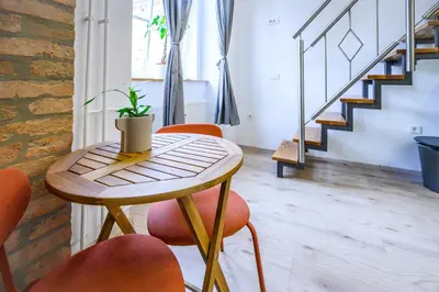 a small table with orange chairs and a plant on it at The Amazing Loft in Ljubljana