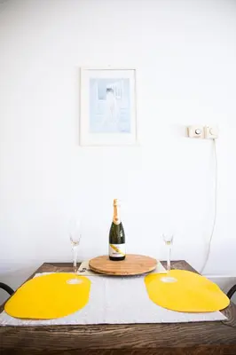 a table with two yellow napkins and a bottle of wine at Sončni apartma in Bovec