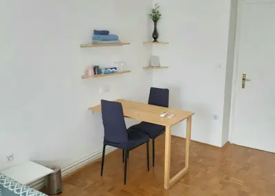 a wooden table and two chairs in a room at ROOMserv in Ljubljana
