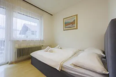 a bedroom with a bed with white sheets and a window at Papas Apartment in Lesce