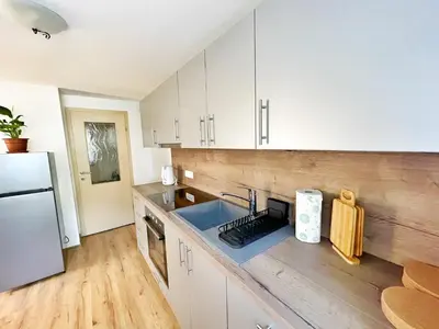 a kitchen with white cabinets and a sink and a refrigerator at Papas Apartment in Lesce