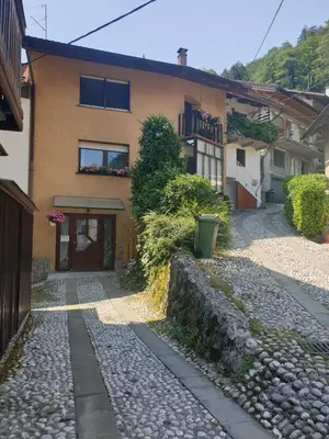 a house with a stone path in front of a building at Apartma na klancu in Kobarid