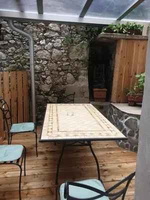 a table and chairs on a patio with a stone wall at Apartma na klancu in Kobarid
