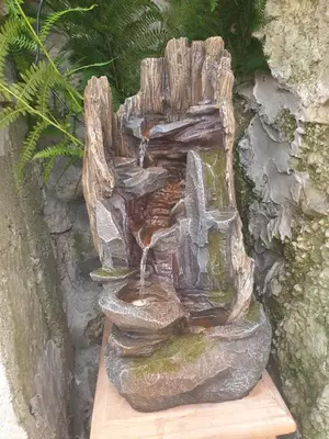 a statue of a water fountain in a garden at Apartma na klancu in Kobarid