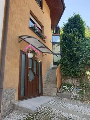 a house with a door and flowers in a window at Apartma na klancu in Kobarid