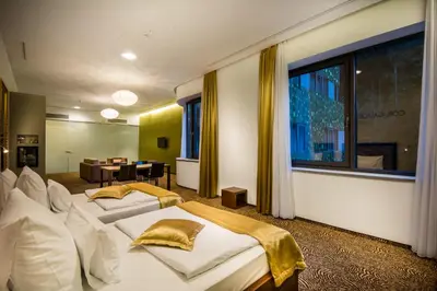 a hotel room with two beds and a table at Rimske Terme Resort - Hotel Rimski dvor in Rimske Toplice