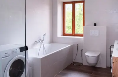 a bathroom with a tub and a washing machine at Riverview Lodge in Bohinj