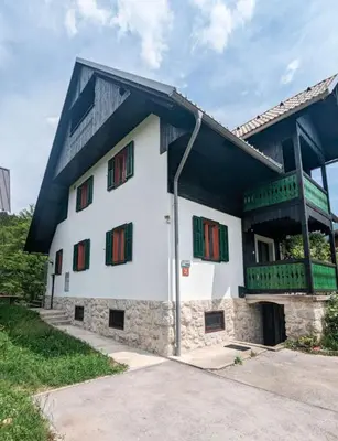 a white building with red and green windows at Riverview Lodge in Bohinj