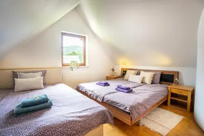 two twin beds in a attic bedroom with a window at View apartment Lenart in Bohinj
