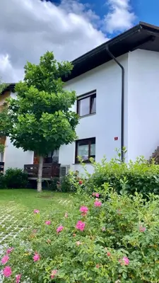 a white house with a tree and pink flowers at Lanima in Bled