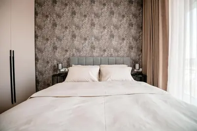 a bedroom with a large white bed with a wallpaper at Sodoben apartma v centru Ljubljane in Ljubljana