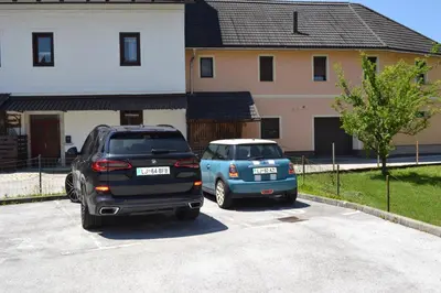 two cars parked in a parking lot in front of a house at APARTMA VODNIK in Bohinj