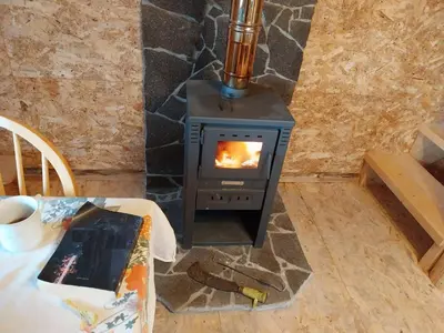 a wood stove in a room with a table at Cowboy House at Ranch Lambergar in Gabrovka