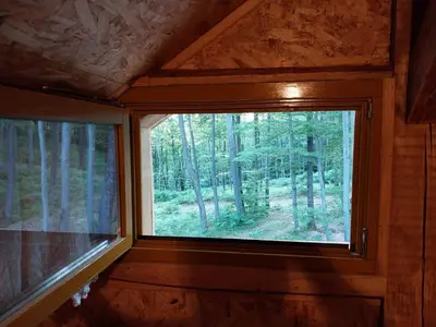 a window in a cabin with a view of the woods at Cowboy House at Ranch Lambergar in Gabrovka