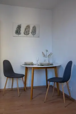 a dining room table with two chairs and a table with plates and glasses at Small but cozy apartment in Maribor