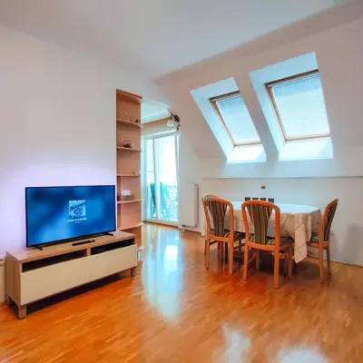 a living room with a table and chairs and a tv at Alpine Nest in Bled