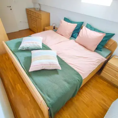 a large bed with pink and blue pillows on it at Alpine Nest in Bled