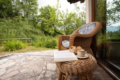 a wicker chair sitting on a porch with a book at At Peskar's a charming countryside house in Podbrdo