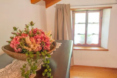 a bowl of flowers on a table with a window at Country House Lastovka in Tolmin