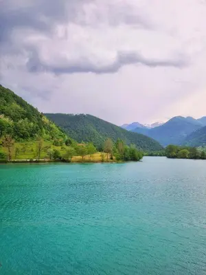 a large blue lake with mountains in the background at Country House Lastovka in Tolmin