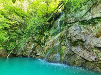 a waterfall on the side of a mountain with blue water at Country House Lastovka in Tolmin