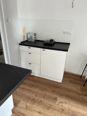 a white kitchen with a black counter top at Gostilna in apartmaji Zlati lev - Maribor in Maribor