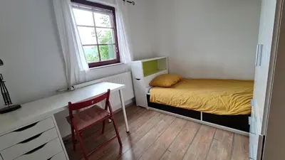 a small bedroom with a bed and a desk and a window at Apartma pri babici in Slovenj Gradec