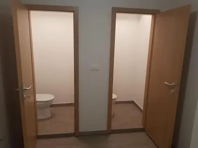 a bathroom with two doors and a toilet in it at Apartma pri babici in Slovenj Gradec