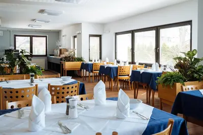a restaurant with blue tables and chairs and windows at Hotel GH Kolinska in Bled