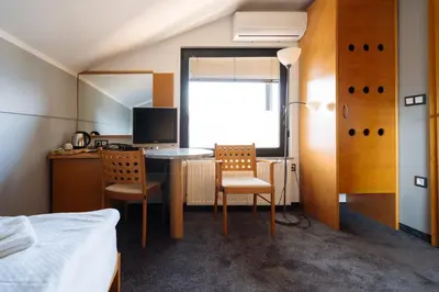 a bedroom with a desk with two chairs and a bed at Hotel GH Kolinska in Bled