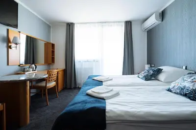 a hotel room with two beds and a desk at Hotel GH Kolinska in Bled