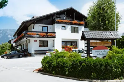 a building with cars parked in a parking lot at Hotel GH Kolinska in Bled