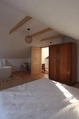 a bedroom with a large bed and a bathroom at Hiška pod Klumpo in Ormoz