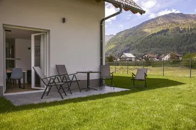 a patio with chairs and a table in the grass at Chic Apartments with Finnish Sauna and Jacuzzi in Kranjska Gora