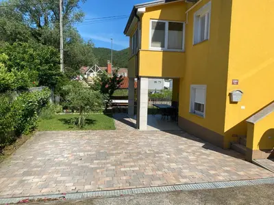 a yellow house with a brick walkway next to it at Apartma Mira in Zgornje Škofije