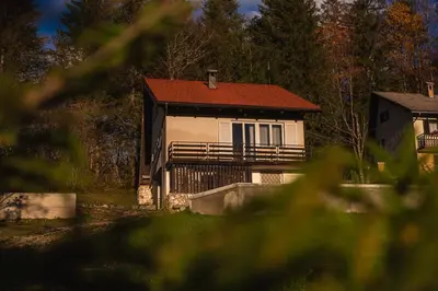 a house with a red roof and a fence at Cosy countryside cottage with indoor fireplace in Sodražica