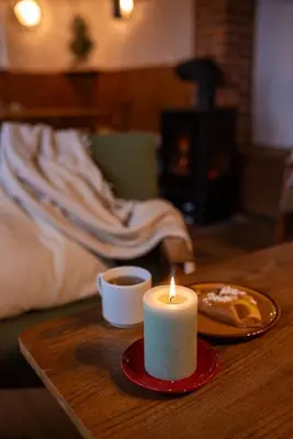 a candle sitting on a table with a cup of coffee at Cosy countryside cottage with indoor fireplace in Sodražica