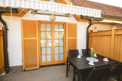 a patio with wooden doors and a table at POČITNIŠKI APARTMAJI - Vijolica 2 in Moravske Toplice in Moravske Toplice