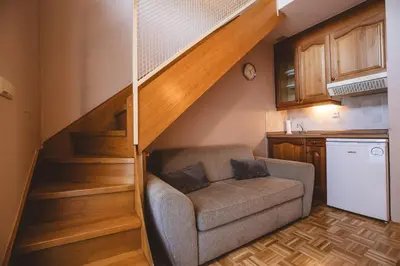 a living room with a couch under a staircase at POČITNIŠKI APARTMAJI - Vijolica 2 in Moravske Toplice in Moravske Toplice