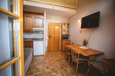 a kitchen with a wooden table and a television on the wall at POČITNIŠKI APARTMAJI - Vijolica 2 in Moravske Toplice in Moravske Toplice