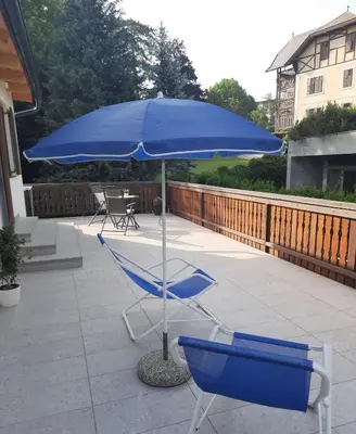 a blue umbrella and two chairs on a patio at UpArt Bled in Bled