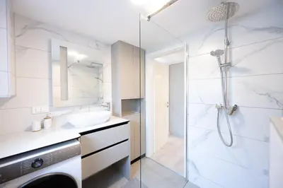 a bathroom with a shower and a sink and a washing machine at The Nice Apartment in Domžale