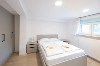a white bedroom with a white bed and a window at The Nice Apartment in Domžale